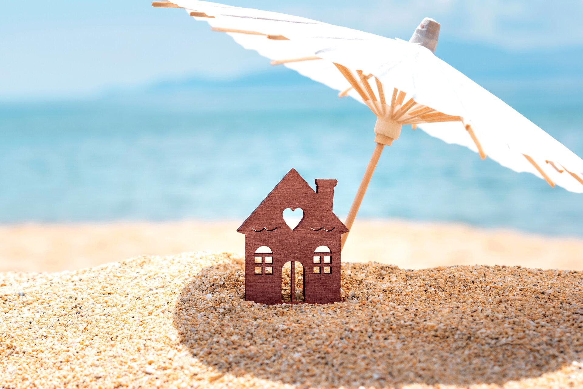 Miniatur-Haus und Sonnenschirm am Strand