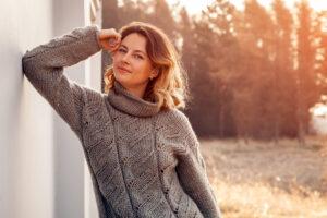 Nahaufnahme einer Frau in braunen Strickpullover aus natürlicher Wolle und Jeans