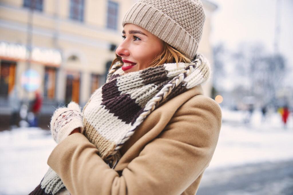 Dame genießt kaltes, verschneites Wetter in warmer Kleidung, in der Stadt und geht alleine im Freien spazieren.