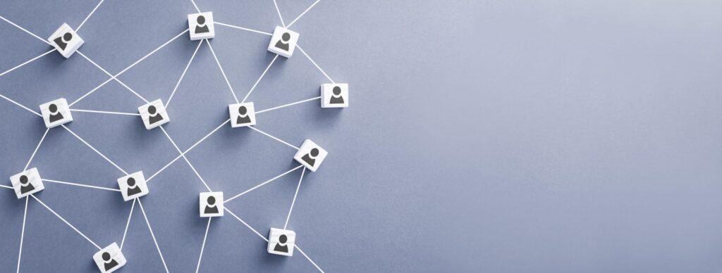 Symbolische Darstellung von Networking mit verbundenen Personen-Icons auf einem blauen Hintergrund, die erfolgreiche Verbindungen und Beziehungen zeigen