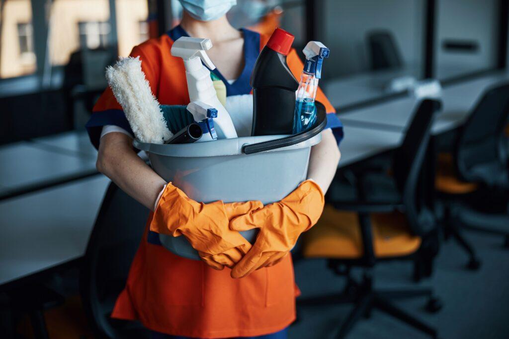 Eine Frau hält verschiedene Putzutensilien in der Hand