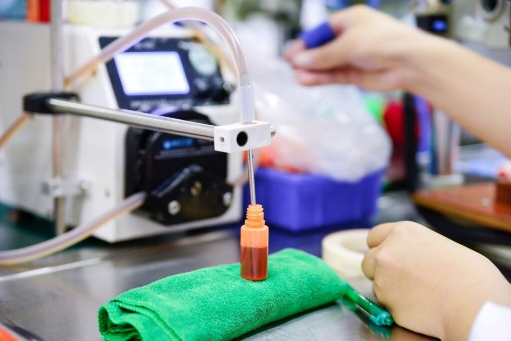 Nahaufnahme einer Maschine beim Abfüllen eines Liquids in eine Flasche, begleitet von präziser Handarbeit.