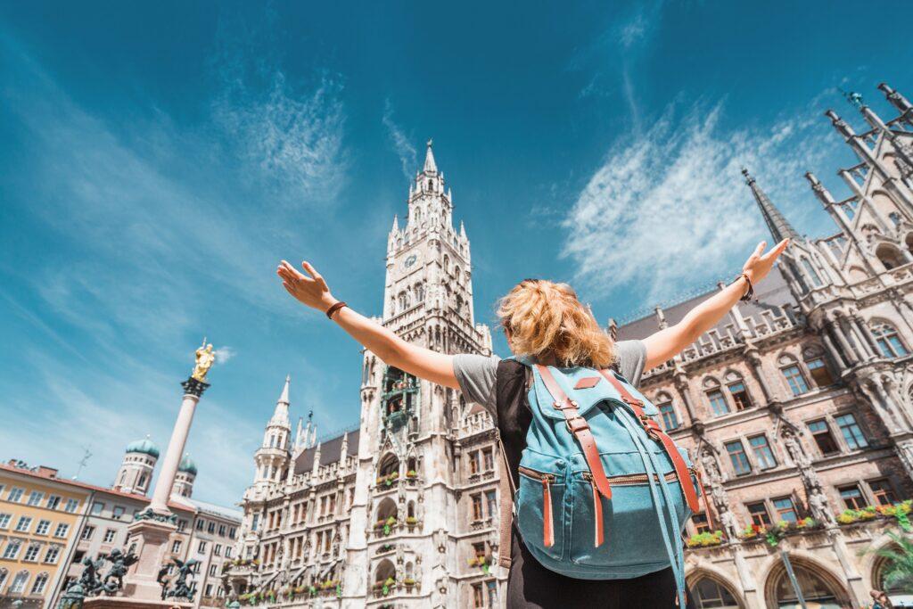 Mädchen mit Rucksack vor dem Neuen Rathaus in München, Blick nach oben auf Sehenswürdigkeiten bei Klassenfahrt