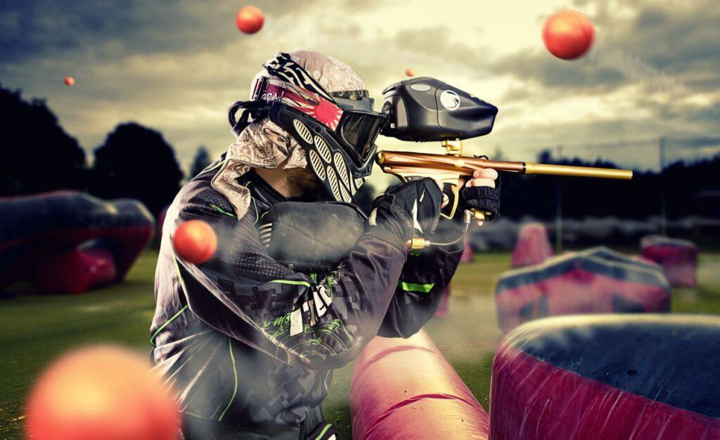 Dynamische Szene eines Spielers beim Paintball Training mit Magfed Markierer, fliegende Paintballs und sportliche Action im Freien