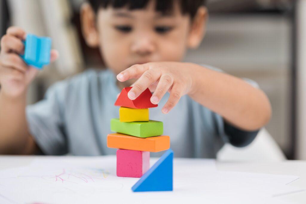Kleinkind stapelt bunte Holzklötze und Formen | Grundschule Berlin